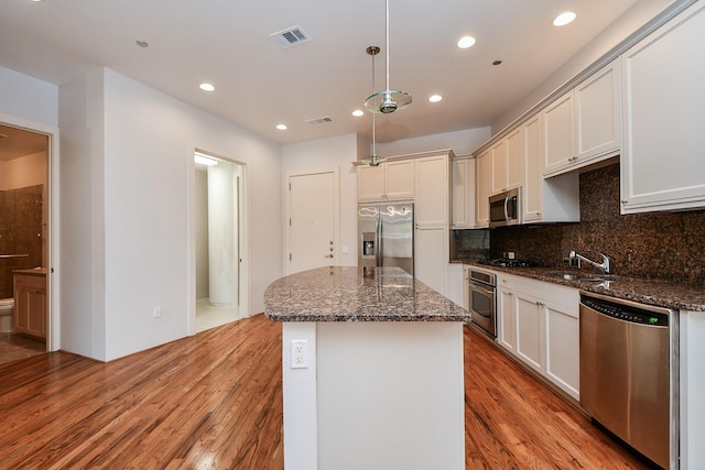 5005 Hidalgo St Unit 210, Houston, TX 77056 - kitchen with stainless steel appliances, recessed lighting, light wood-type flooring, a center island, and backsplash