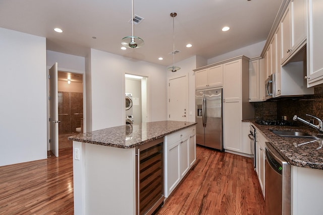 5005 Hidalgo St Unit 210, Houston, TX 77056 - kitchen with stainless steel appliances, beverage cooler, stacked washer and clothes dryer, wood finished floors, and recessed lighting