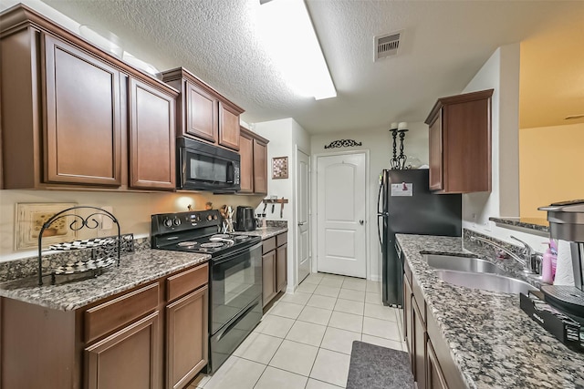 21118 Baltic Rain Dr, Hockley, TX 77447 - kitchen featuring black appliances, light tile patterned floors, dark stone counters, and a textured ceiling