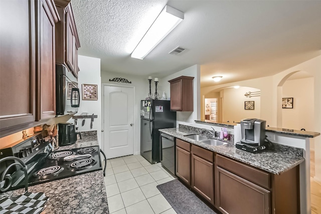 21118 Baltic Rain Dr, Hockley, TX 77447 - kitchen featuring black appliances, a peninsula, light tile patterned floors, dark stone countertops, and arched walkways