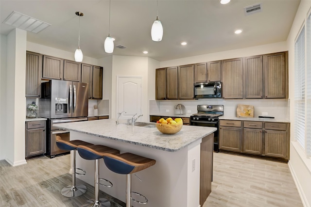 3905 Chartham Ln, Pearland, TX 77584 - kitchen featuring black microwave, stainless steel fridge with ice dispenser, gas range oven, tasteful backsplash, and light wood-style flooring