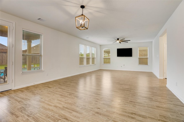 3905 Chartham Ln, Pearland, TX 77584 - unfurnished living room featuring plenty of natural light, light wood-style flooring, a chandelier, and a ceiling fan