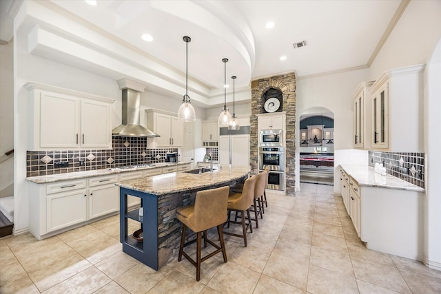 5214 Bristol Bank Ct, Houston, TX 77041 - kitchen featuring wall chimney exhaust hood, appliances with stainless steel finishes, tasteful backsplash, crown molding, and a kitchen island with sink