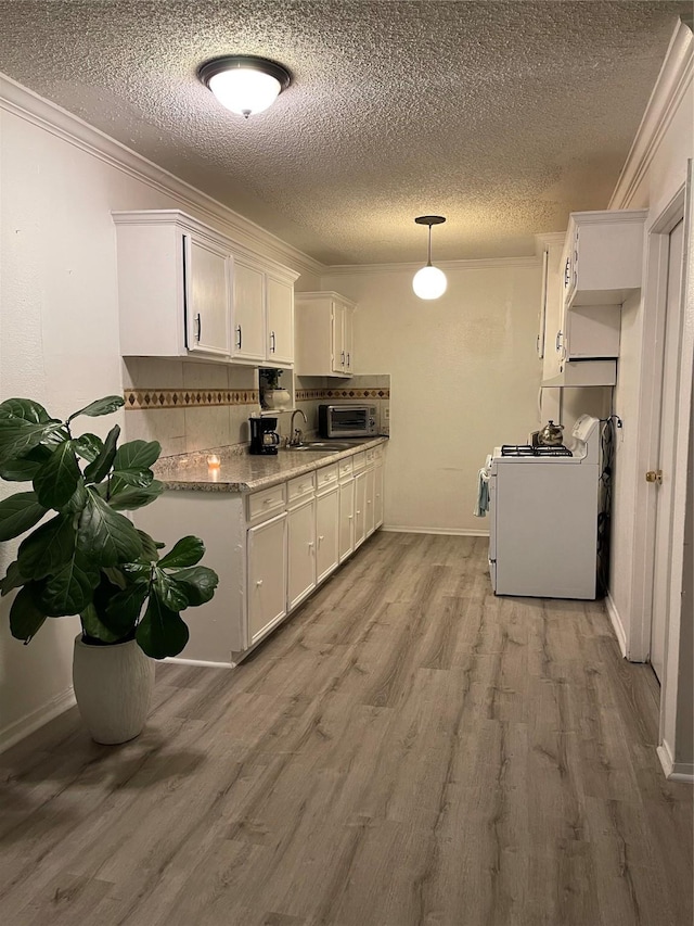 6101 Maywood Dr, Houston, TX 77053 - kitchen featuring white range, crown molding, light wood finished floors, stainless steel microwave, and white cabinets