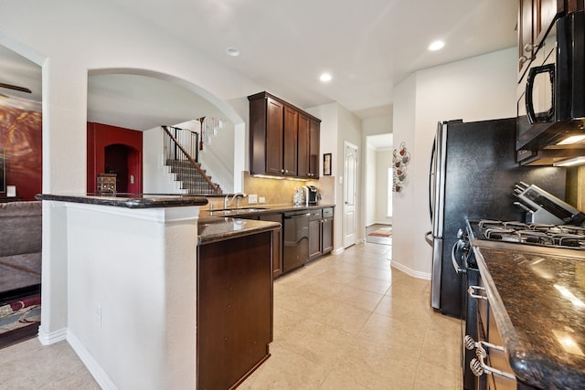 7910 Brooks Crossing Dr, Baytown, TX 77521 - kitchen with gas stove, dishwasher, black microwave, arched walkways, and dark stone countertops