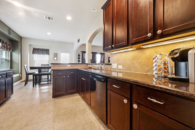 7910 Brooks Crossing Dr, Baytown, TX 77521 - kitchen featuring dishwashing machine, backsplash, dark stone counters, light tile patterned flooring, and arched walkways