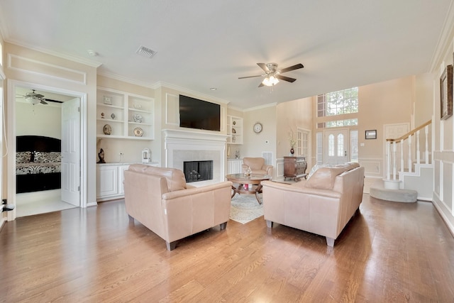 4106 Alice Dr, Sugar Land, TX 77478 - living area featuring ceiling fan, a fireplace, built in shelves, light wood finished floors, and a decorative wall
