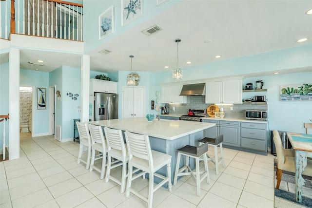 18614 Warrior Rd, Galveston, TX 77554 - kitchen featuring stainless steel appliances, wall chimney range hood, light tile patterned flooring, light countertops, and recessed lighting