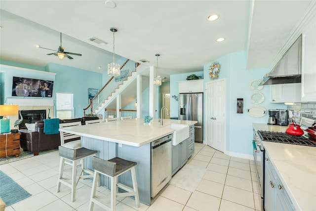 18614 Warrior Rd, Galveston, TX 77554 - kitchen featuring stainless steel appliances, a glass covered fireplace, light tile patterned floors, a breakfast bar area, and open floor plan