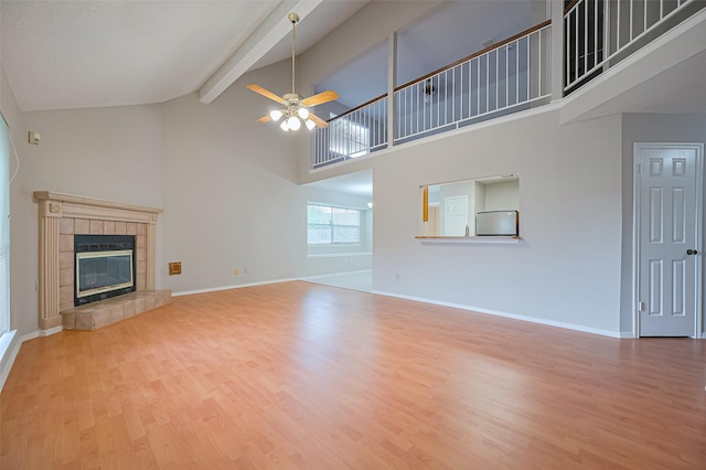 2415 Pebbledowne Cir, Sugar Land, TX 77478 - unfurnished living room with a ceiling fan, high vaulted ceiling, wood finished floors, beam ceiling, and a tiled fireplace