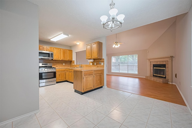 2415 Pebbledowne Cir, Sugar Land, TX 77478 - kitchen with appliances with stainless steel finishes, a chandelier, light countertops, open floor plan, and a tile fireplace