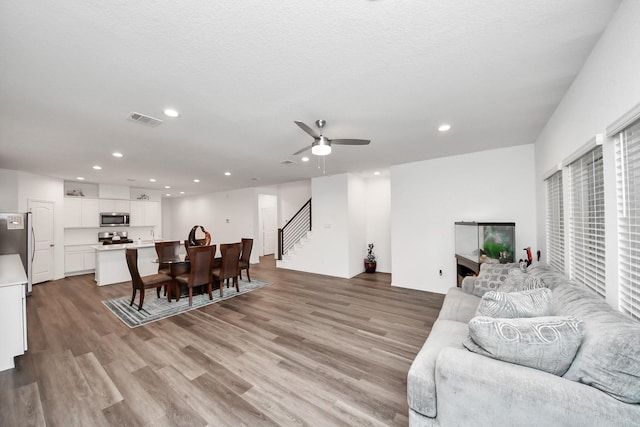 4985 Blue Beetle Ridge Dr, Katy, TX 77493 - living room featuring stairs, light wood-style floors, recessed lighting, and ceiling fan