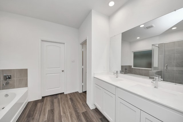 4985 Blue Beetle Ridge Dr, Katy, TX 77493 - bathroom featuring a garden tub, wood finished floors, double vanity, recessed lighting, and tiled shower
