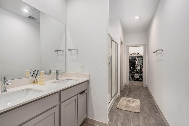 12810 Barnesbury Ln, Houston, TX 77047 - bathroom featuring wood finished floors, a shower stall, double vanity, and a spacious closet