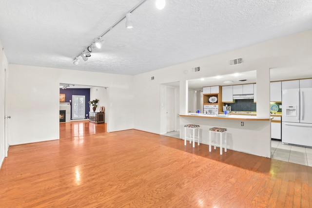 1202 Fay Rd, Kemah, TX 77565 - unfurnished living room with a textured ceiling, light wood-style floors, and a warm lit fireplace
