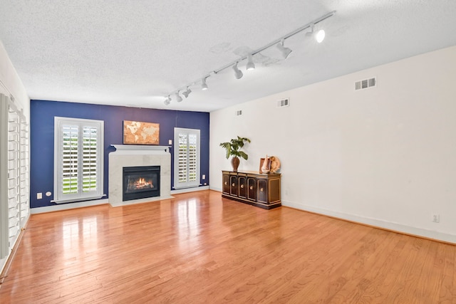 1202 Fay Rd, Kemah, TX 77565 - unfurnished living room featuring wood finished floors, a textured ceiling, track lighting, and a tile fireplace