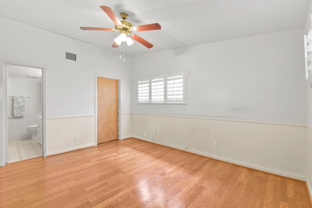 1202 Fay Rd, Kemah, TX 77565 - unfurnished bedroom featuring wood finished floors, a wainscoted wall, ensuite bath, and ceiling fan