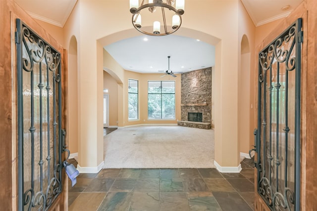 26150 Crown Ranch Blvd, Montgomery, TX 77316 - entryway with arched walkways, dark colored carpet, ceiling fan, a chandelier, and a stone fireplace