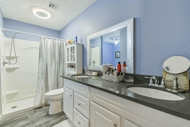 637 Mosswood Dr, Conroe, TX 77302 - bathroom featuring a textured wall, double vanity, a shower with curtain, wood finished floors, and a textured ceiling