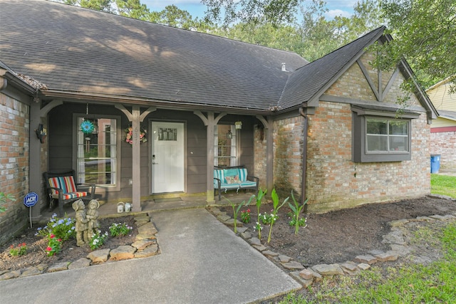 637 Mosswood Dr, Conroe, TX 77302 - view of exterior entry with a shingled roof, brick siding, and covered porch