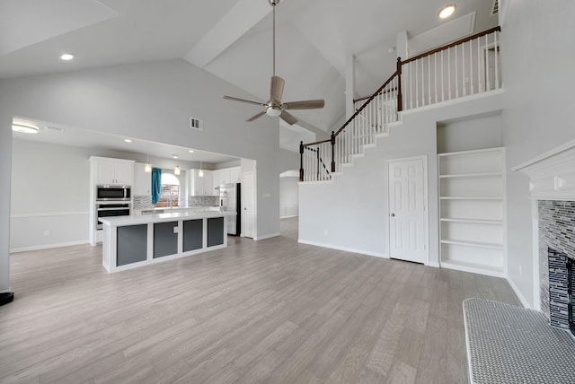 412 Belmont Ct, Lewisville, TX 75067 - unfurnished living room with a ceiling fan, light wood-style flooring, a tile fireplace, high vaulted ceiling, and built in shelves