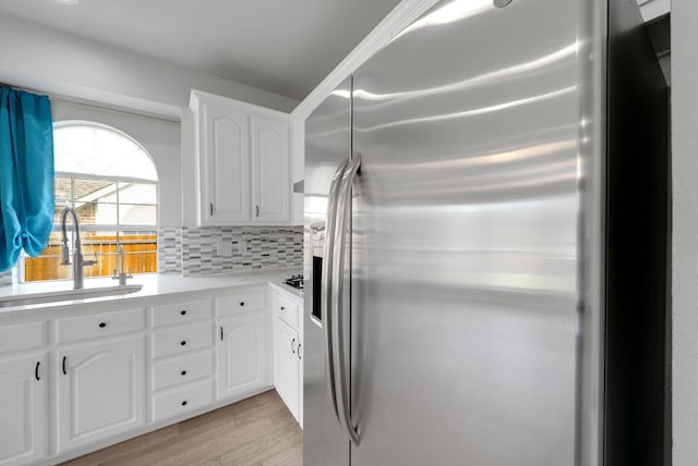 412 Belmont Ct, Lewisville, TX 75067 - kitchen featuring stainless steel refrigerator with ice dispenser, light wood-style flooring, white cabinetry, backsplash, and light countertops
