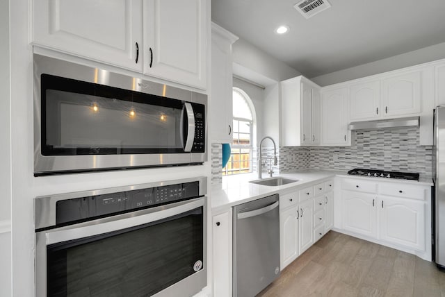 412 Belmont Ct, Lewisville, TX 75067 - kitchen with appliances with stainless steel finishes, white cabinets, light countertops, light wood-style flooring, and recessed lighting