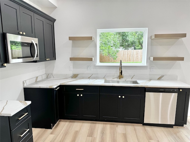 2328 Wavell St, Houston, TX 77088 - kitchen with appliances with stainless steel finishes, open shelves, light stone counters, dark cabinetry, and light wood-style floors