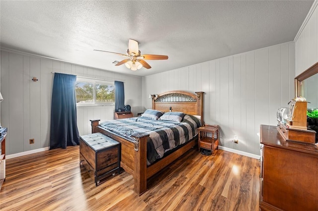 446 Norwood St, Marlin, TX 76661 - bedroom with light wood finished floors, a textured ceiling, a decorative wall, and a ceiling fan