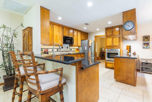 1211 Tall Pines Dr, Friendswood, TX 77546 - kitchen featuring appliances with stainless steel finishes, a peninsula, brown cabinetry, tasteful backsplash, and recessed lighting