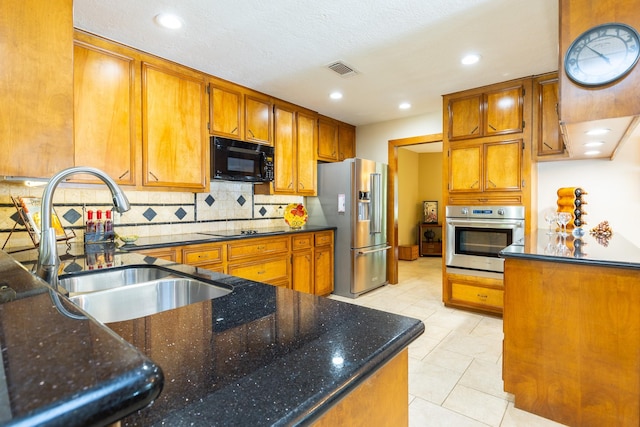 1211 Tall Pines Dr, Friendswood, TX 77546 - kitchen with black appliances, brown cabinets, backsplash, dark stone counters, and recessed lighting