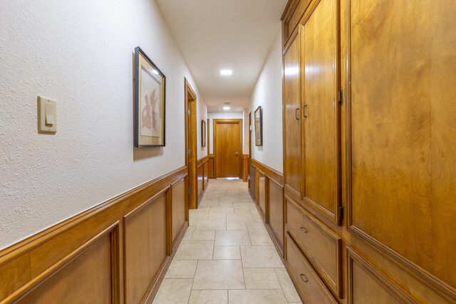 1211 Tall Pines Dr, Friendswood, TX 77546 - corridor featuring wainscoting, a decorative wall, recessed lighting, and light stone finish floors