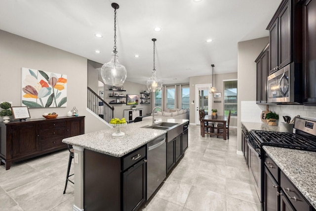 29522 Westhope Dr, Spring, TX 77386 - kitchen featuring stainless steel appliances, recessed lighting, decorative backsplash, light stone counters, and a kitchen island with sink