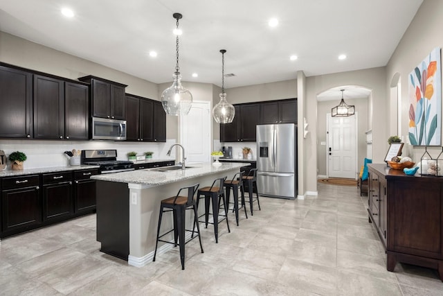 29522 Westhope Dr, Spring, TX 77386 - kitchen with stainless steel appliances, a breakfast bar, arched walkways, an island with sink, and light stone counters