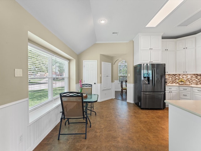 3139 Prairiestone Trail Ln, Katy, TX 77450 - kitchen featuring refrigerator with ice dispenser, white cabinetry, tasteful backsplash, light countertops, and arched walkways