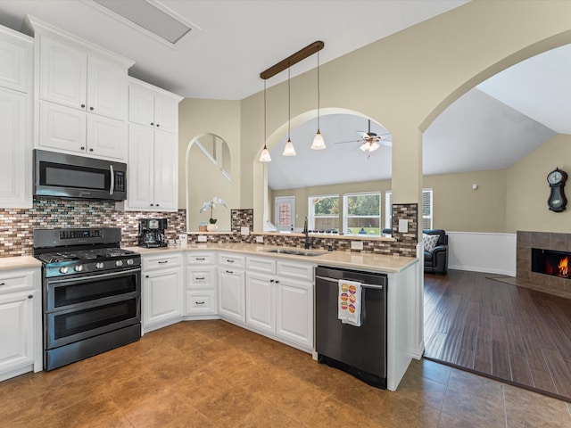 3139 Prairiestone Trail Ln, Katy, TX 77450 - kitchen with appliances with stainless steel finishes, ceiling fan, lofted ceiling, a tiled fireplace, and wainscoting
