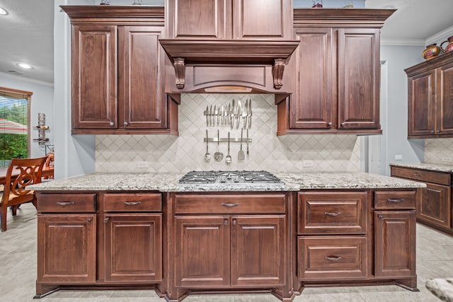 207 Fox Squirrel Ct, Pinehurst, TX 77362 - kitchen featuring ornamental molding, stainless steel gas stovetop, light stone counters, backsplash, and dark brown cabinets