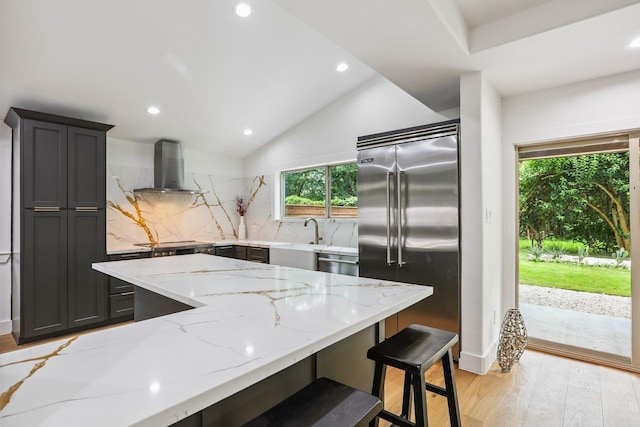 4543 Warm Springs Rd, Houston, TX 77035 - kitchen with appliances with stainless steel finishes, wall chimney range hood, light stone counters, tasteful backsplash, and light wood-style flooring