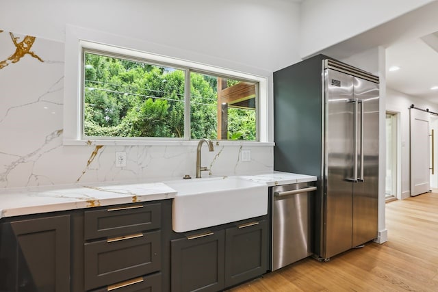 4543 Warm Springs Rd, Houston, TX 77035 - kitchen featuring appliances with stainless steel finishes, tasteful backsplash, light stone counters, light wood-type flooring, and recessed lighting
