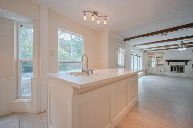 5318 Foresthaven Dr, Houston, TX 77066 - kitchen featuring a textured ceiling, open floor plan, a fireplace, a center island with sink, and light countertops