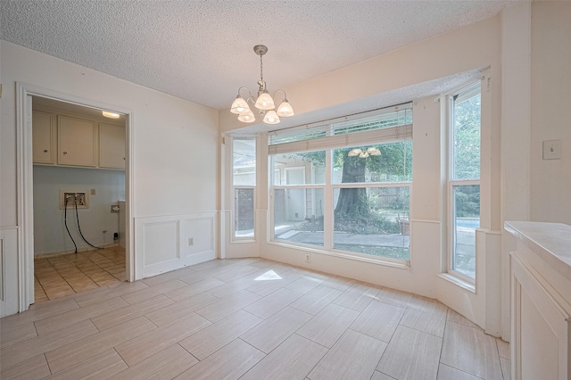 5318 Foresthaven Dr, Houston, TX 77066 - unfurnished dining area featuring a chandelier, a textured ceiling, wainscoting, wood tiled floors, and a decorative wall