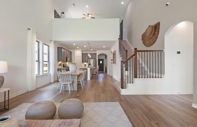 14595 Clementine Hall Dr, Conroe, TX 77378 - dining area with arched walkways, light wood-style flooring, a ceiling fan, a towering ceiling, and stairs