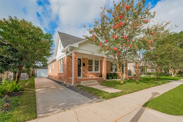 1026 W Cottage St, Houston, TX 77009 - view of front facade with brick siding, a front yard, covered porch, an outbuilding, and a garage