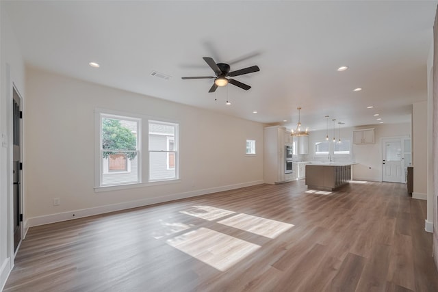 1026 W Cottage St, Houston, TX 77009 - unfurnished living room featuring plenty of natural light, ceiling fan, a chandelier, light wood-style flooring, and recessed lighting