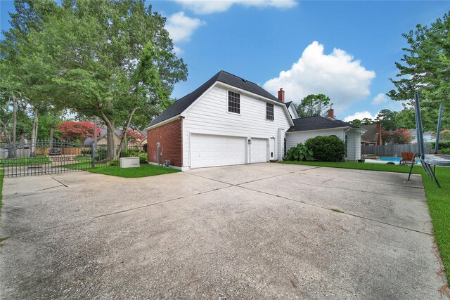 2206 Hickory Park Dr, Kingwood, TX 77345 - view of home's exterior featuring driveway, an attached garage, a chimney, and brick siding