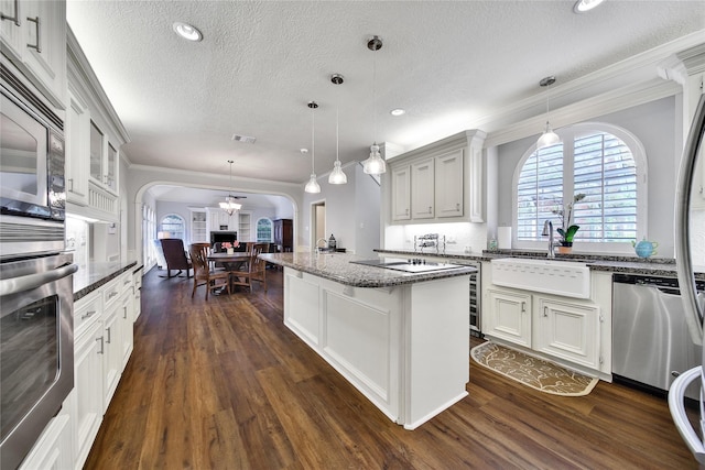 2206 Hickory Park Dr, Kingwood, TX 77345 - kitchen with stainless steel appliances, arched walkways, a textured ceiling, ornamental molding, and dark wood finished floors