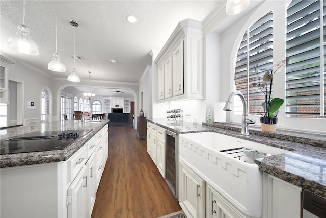 2206 Hickory Park Dr, Kingwood, TX 77345 - kitchen featuring black electric cooktop, open floor plan, dark wood finished floors, crown molding, and white cabinets