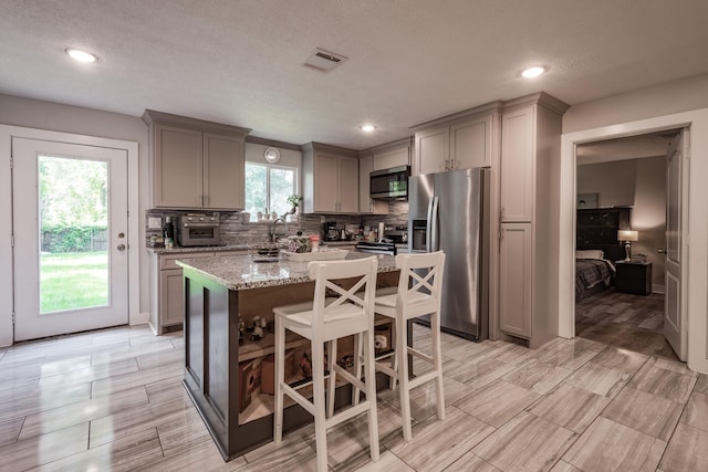 26752 Diamond Sq, Splendora, TX 77372 - kitchen with stainless steel appliances, gray cabinetry, a center island, tasteful backsplash, and recessed lighting