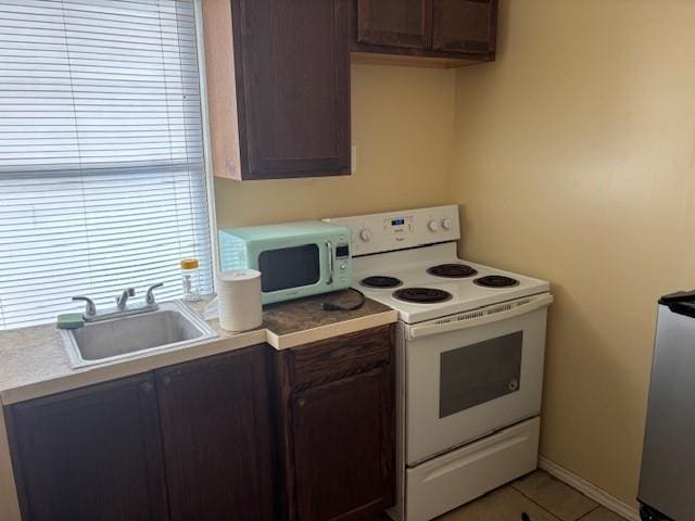 26752 Diamond Sq, Splendora, TX 77372 - kitchen featuring white electric range oven, light countertops, light tile patterned flooring, and dark brown cabinetry