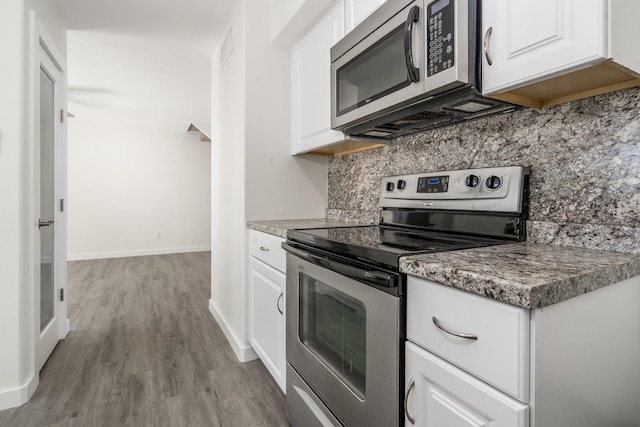 12239 Glenview Dr, Montgomery, TX 77356 - kitchen featuring stainless steel appliances, white cabinetry, wood finished floors, and decorative backsplash